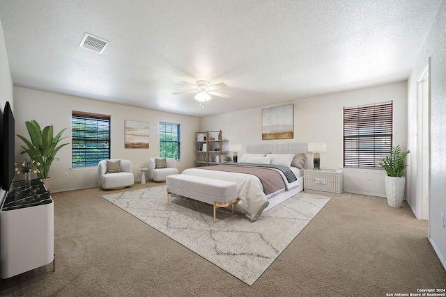 carpeted bedroom featuring ceiling fan and a textured ceiling