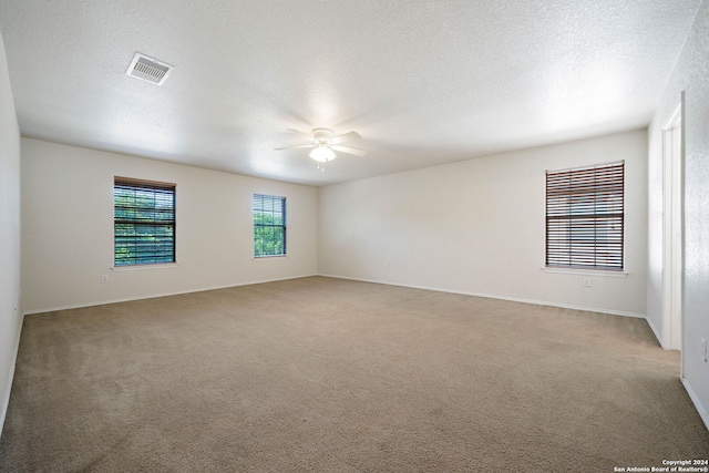 carpeted spare room featuring ceiling fan and a textured ceiling