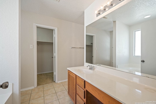 bathroom featuring tile floors, a bathtub, vanity, and a textured ceiling