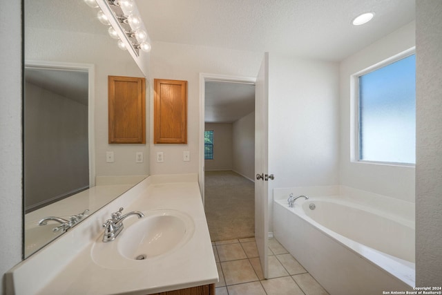 bathroom with a bath to relax in, tile floors, vanity, and a textured ceiling