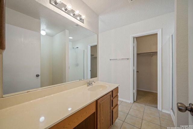 bathroom featuring tile flooring, vanity, a shower with shower door, and a textured ceiling