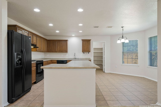 kitchen with a center island, light tile floors, extractor fan, black appliances, and pendant lighting