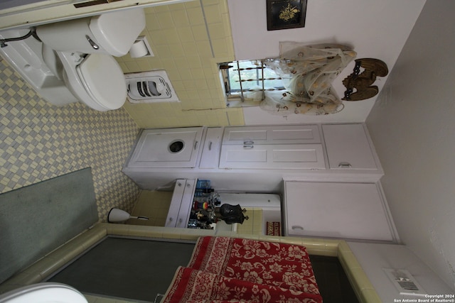 bathroom featuring toilet, tile floors, and tile walls