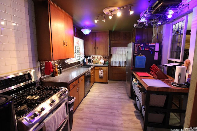 kitchen with light wood-type flooring, stainless steel appliances, sink, tasteful backsplash, and track lighting