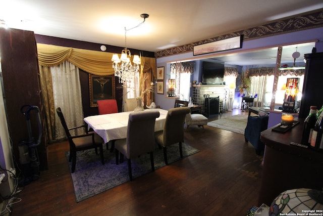 dining space featuring a fireplace, dark hardwood / wood-style flooring, and an inviting chandelier