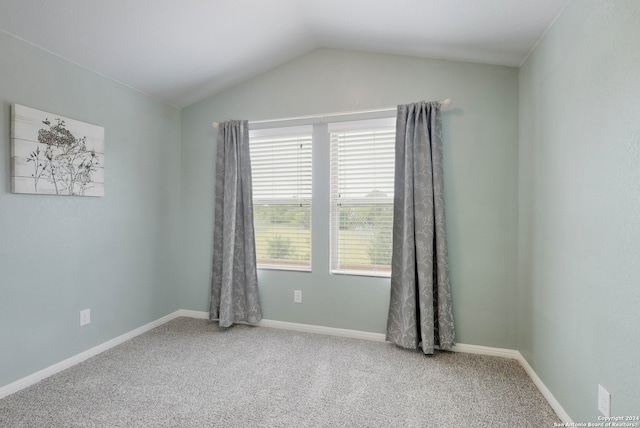 spare room featuring light colored carpet and lofted ceiling