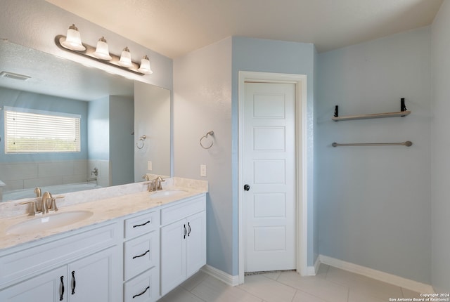 bathroom with large vanity, a textured ceiling, a tub, double sink, and tile floors