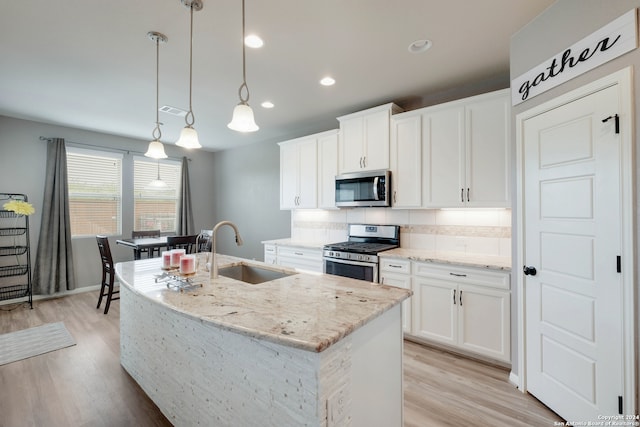 kitchen featuring appliances with stainless steel finishes, white cabinetry, sink, pendant lighting, and light wood-type flooring