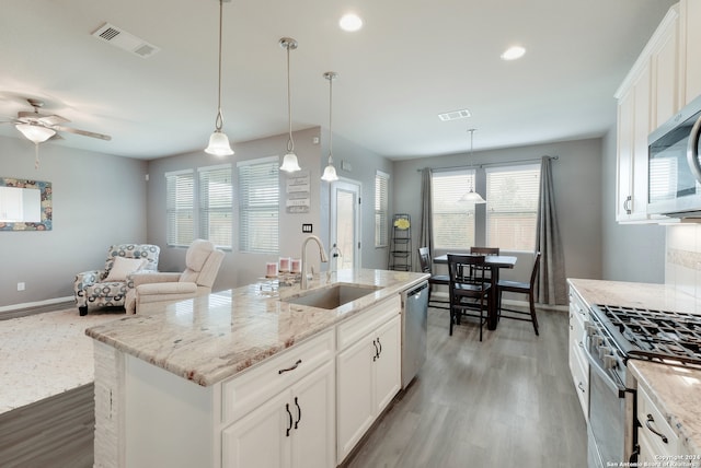 kitchen featuring pendant lighting, a kitchen island with sink, white cabinetry, sink, and hardwood / wood-style flooring