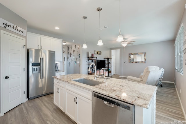 kitchen with light wood-type flooring, white cabinetry, stainless steel appliances, sink, and an island with sink