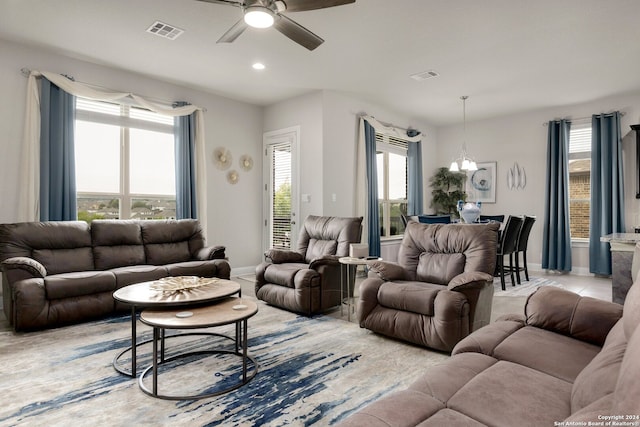 tiled living room featuring ceiling fan with notable chandelier