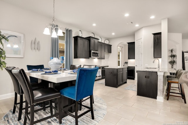 dining room with sink, light tile floors, and a chandelier