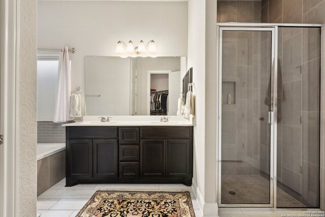 bathroom with dual sinks, tile flooring, vanity with extensive cabinet space, and plus walk in shower