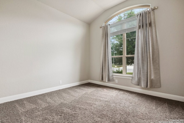 carpeted spare room with vaulted ceiling