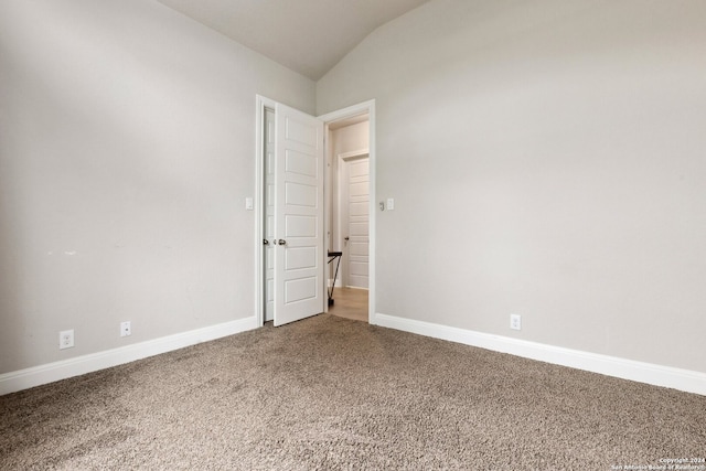 carpeted empty room with vaulted ceiling