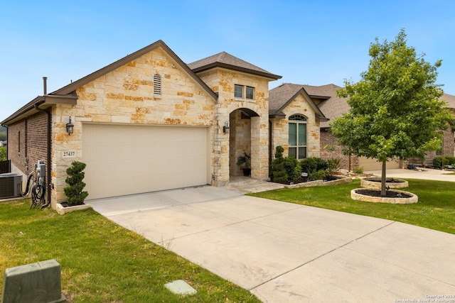 view of front of house featuring a front yard, a garage, and central AC