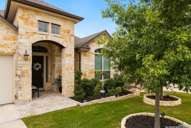 entrance to property featuring a lawn and a garage