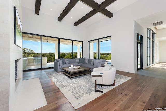 living room featuring a towering ceiling, beam ceiling, and dark hardwood / wood-style floors