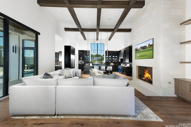 living room featuring a towering ceiling, a fireplace, coffered ceiling, beam ceiling, and dark hardwood / wood-style floors