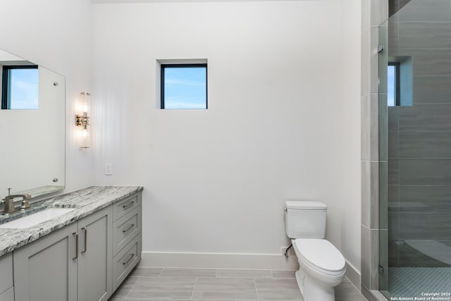 bathroom with walk in shower, toilet, tile floors, and vanity with extensive cabinet space