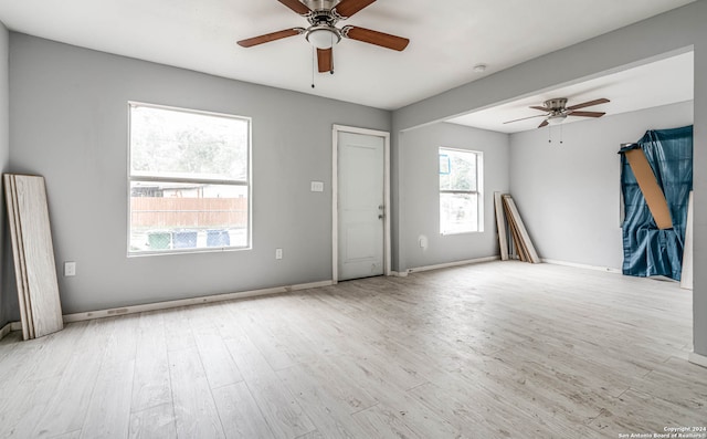 spare room with a healthy amount of sunlight, ceiling fan, and light hardwood / wood-style floors