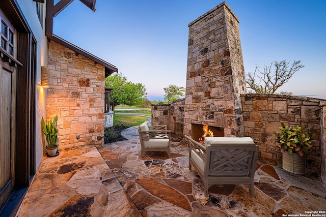 patio terrace at dusk featuring an outdoor stone fireplace