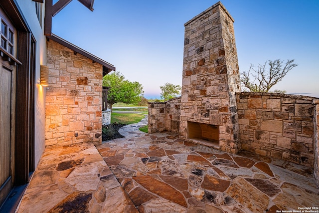 patio terrace at dusk featuring an outdoor stone fireplace