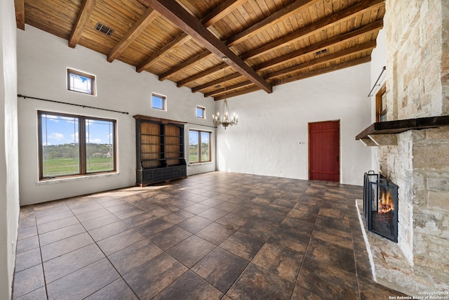 unfurnished living room featuring wood ceiling, a fireplace, a high ceiling, and dark tile floors