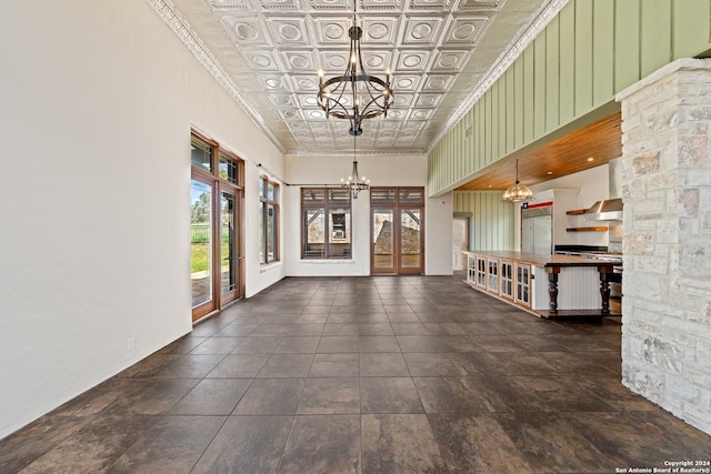 interior space featuring dark tile floors, a towering ceiling, and an inviting chandelier