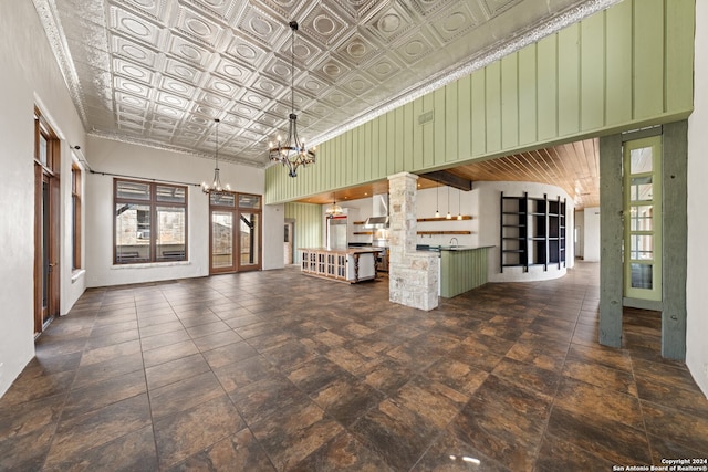 unfurnished living room featuring an inviting chandelier and dark tile flooring