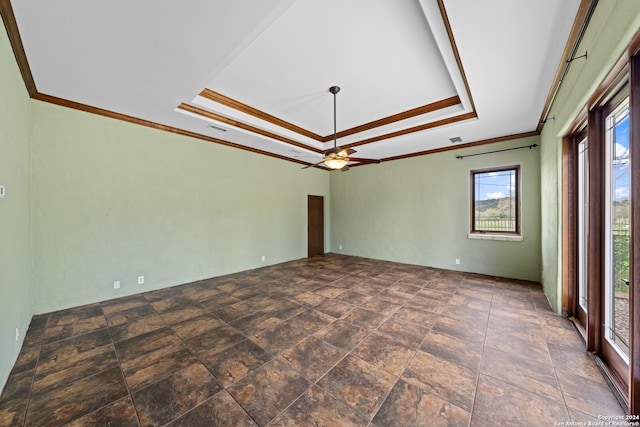 tiled empty room featuring ornamental molding, ceiling fan, and a raised ceiling