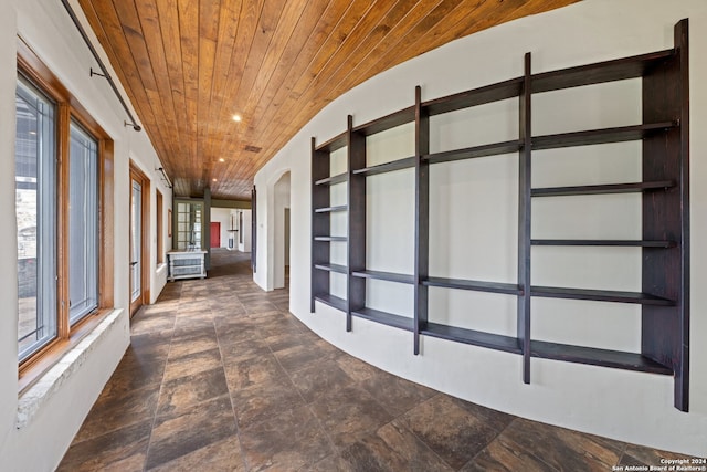 hall with wood ceiling and dark tile flooring