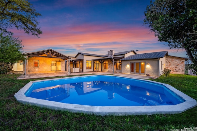 pool at dusk featuring a yard