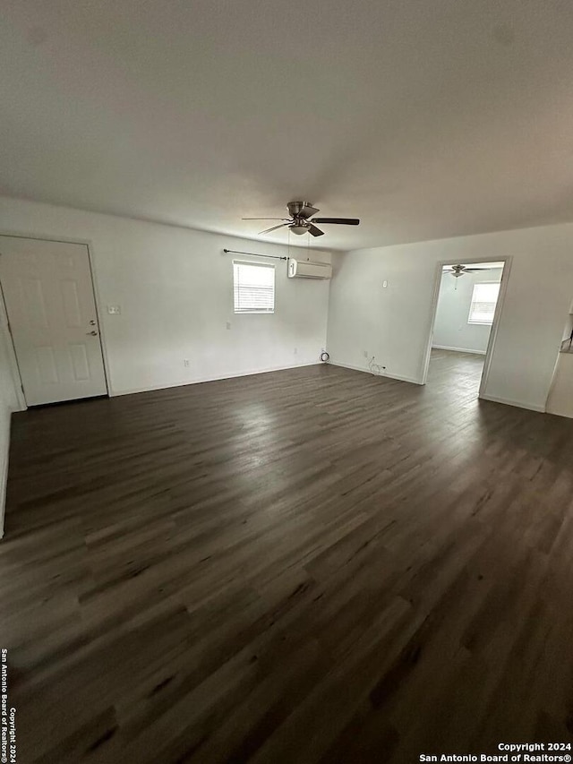 spare room with a wall mounted air conditioner, dark hardwood / wood-style floors, and plenty of natural light