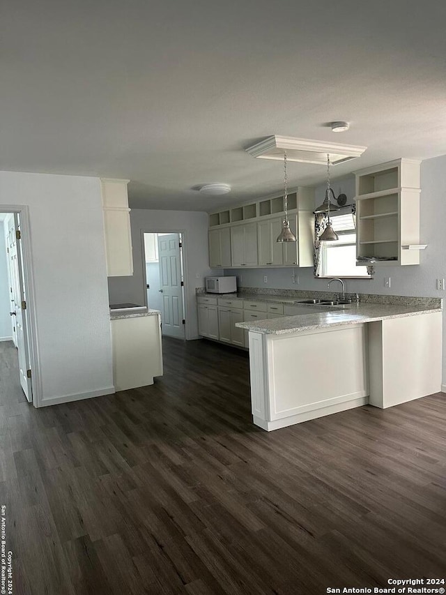 kitchen with white cabinets, kitchen peninsula, dark hardwood / wood-style floors, and hanging light fixtures