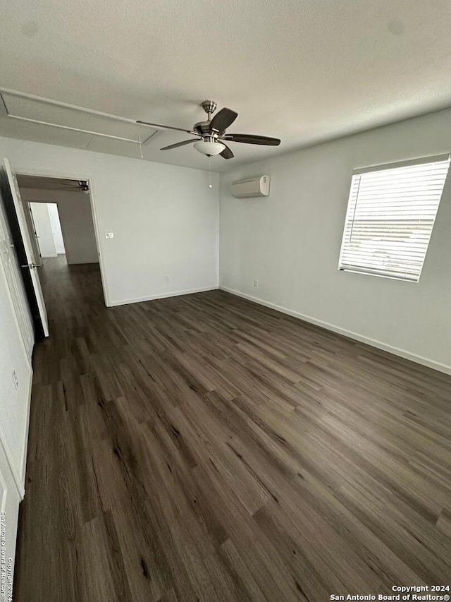 empty room with ceiling fan, a textured ceiling, a wall mounted air conditioner, and dark hardwood / wood-style floors