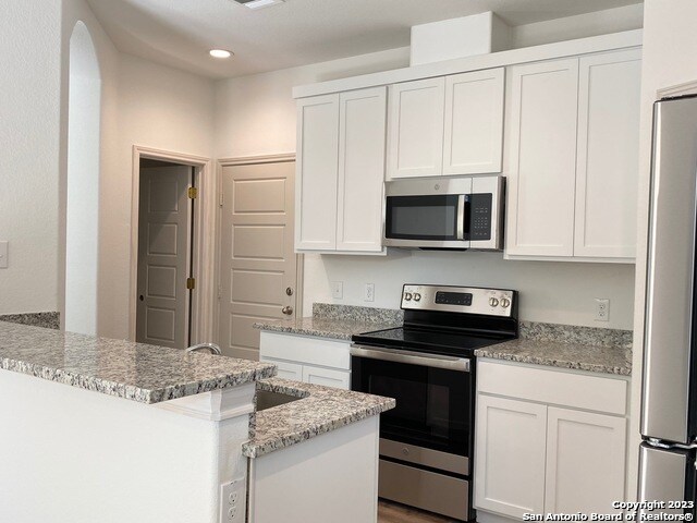 kitchen featuring light stone counters, appliances with stainless steel finishes, and white cabinetry