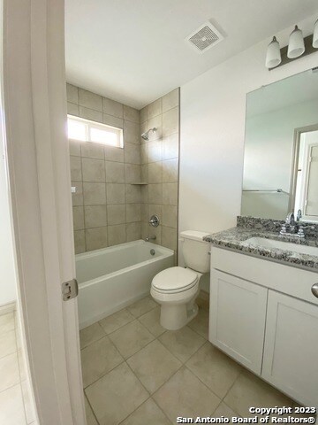 full bathroom with tile floors, toilet, tiled shower / bath combo, and large vanity