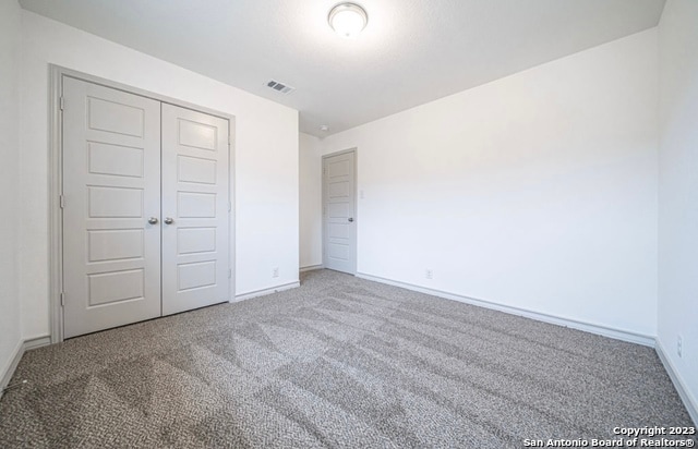 unfurnished bedroom with light colored carpet and a closet