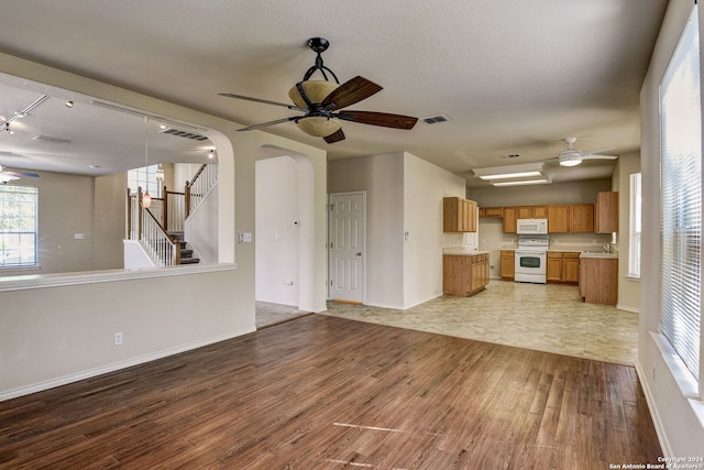 unfurnished living room with wood-type flooring, a textured ceiling, ceiling fan, and rail lighting