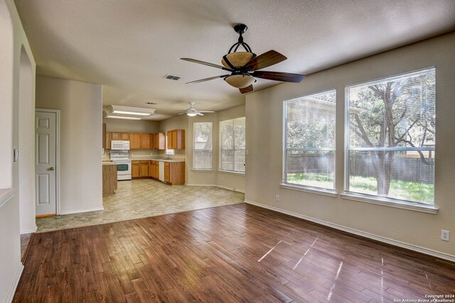 unfurnished living room with sink, ceiling fan, and light tile flooring