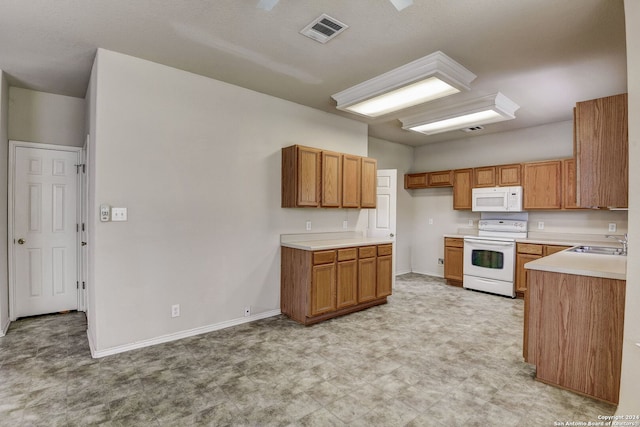 kitchen with sink, white appliances, and light tile flooring