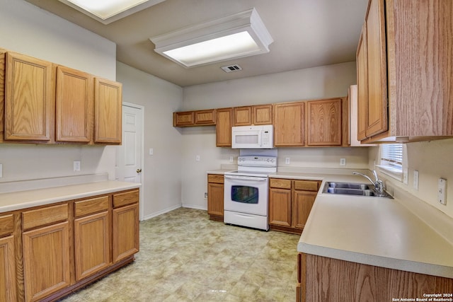 kitchen featuring white appliances, sink, and light tile floors