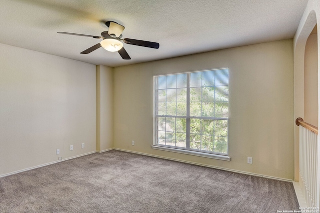 carpeted empty room with a wealth of natural light, ceiling fan, and a textured ceiling