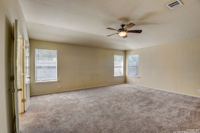 empty room with a wealth of natural light, light colored carpet, and ceiling fan