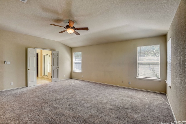 spare room with a textured ceiling, ceiling fan, light carpet, and lofted ceiling