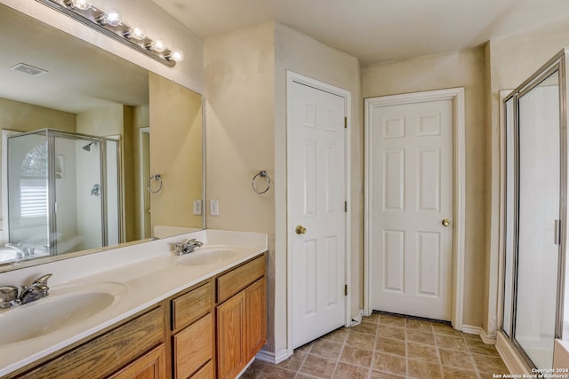 bathroom featuring tile flooring, an enclosed shower, vanity with extensive cabinet space, and dual sinks