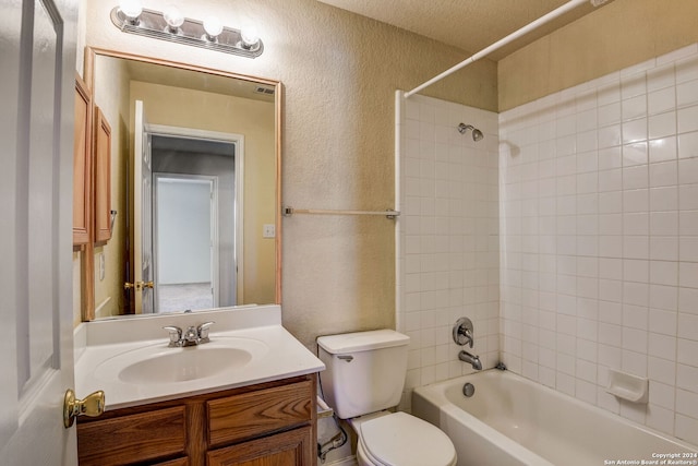 full bathroom with tiled shower / bath, toilet, vanity, and a textured ceiling