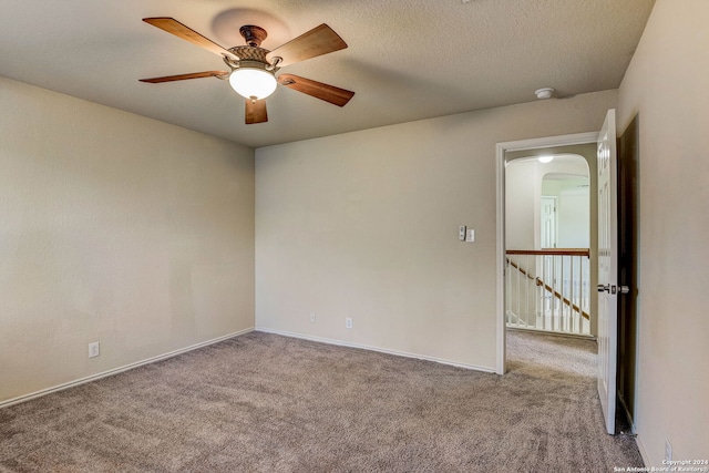 carpeted empty room with ceiling fan and a textured ceiling