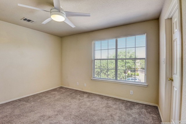 empty room with dark colored carpet, ceiling fan, and a textured ceiling